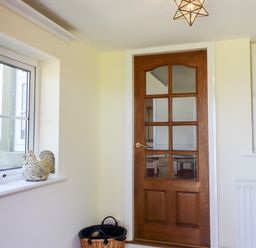 A wooden door with glass panels next to a window with a plant and a decorative rooster on the sill at Buzzards Rest in Stannington near Morpeth