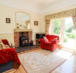 A living room with a fireplace red armchairs and a rug near sliding glass doors at Buzzards Rest in Stannington near Morpeth