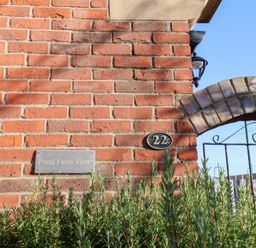 A brick wall with a nameplate and address plaque at Pond Farm View in Hinderwell