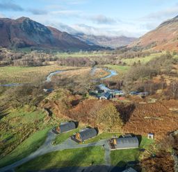 A rural landscape with three small cabins near a winding river and hills at The Stag - Crossgate Luxury Glamping in Hartsop near Glenridding