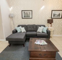 A living room with a gray sectional sofa and a wooden coffee table with magazines at Kizzie Cottage Guyzance near Warkworth