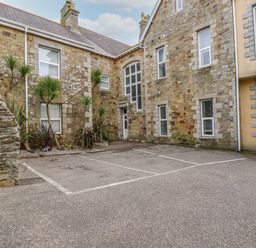 An outdoor parking area with two marked spaces next to a stone building with multiple windows and a door at King Edward's View in Newquay