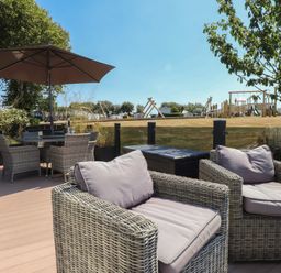 An outdoor patio with seating and a playground in the background at 97 Crugan Llanbedrog