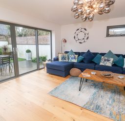 A living room with a blue sectional sofa and wooden coffee table next to glass sliding doors at Tregenna House in St Ives
