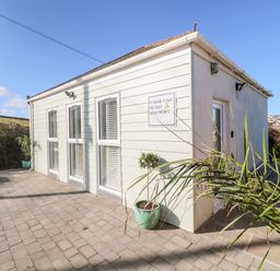 Exterior view of a holiday apartment building with paved patio and potted plants at Perran Pearl A in Perranporth