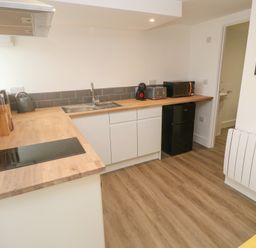 A kitchen with wooden countertops a sink stovetop toaster microwave and small refrigerator at Perran Pearl B in Perranporth