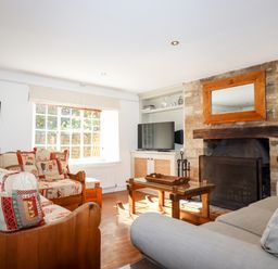 A living room with wooden furniture a stone fireplace and a television at 1 The Lane in Chipping Norton
