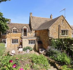 A stone house with a garden patio and outdoor chairs at 1 The Lane in Chipping Norton