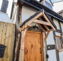 Front entrance of a timber framed house with a wooden door and a black mailbox at 18 Church Street in Llangollen