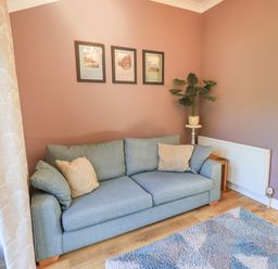 A living room with a sofa and picture frames at The Garden Suite at Fiddler Hall Barn Newby Bridge