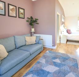 A living room with a sofa and a bed at The Garden Suite at Fiddler Hall Barn, Newby Bridge