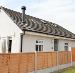 A detached house with a tiled roof and wooden fence surrounding the garden at White Stones in Goadsbarrow near Roose