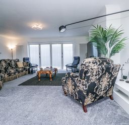 A living room with patterned sofas armchairs a wooden coffee table indoor plant and sculptures at Eildon Lodge in Gosforth