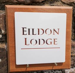 A sign displaying Eildon Lodge on a stone wall in Gosforth