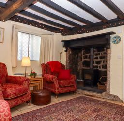 A living room with red armchairs and a fireplace at Fox Hat Cottage in Chagford