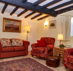 A living room with a sofa, chairs, and lamp at Fox Hat Cottage in Chagford