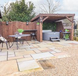 A patio area with a metal table and two chairs a barbecue grill and a covered hot tub at Westfield Lodge in Terrington near Sheriff Hutton