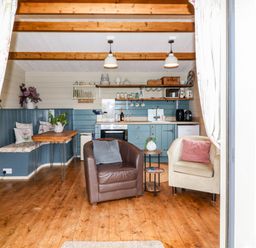 A small kitchen and sitting area with two armchairs a wooden table and shelves at Westfield Lodge in Terrington near Sheriff Hutton