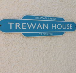 A blue street sign reading Trewan House on a textured white wall at Trewan House in Bryngwran near Rhosneigr Rhosneigr
