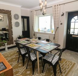 A dining room with a black table and six chairs with cushions and a large mirror on the wall at Trewan House Bryngwran near Rhosneigr Rhosneigr