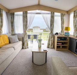 A living room with sofas a coffee table a fireplace and a TV with outside view at Trewan Lodge in Bryngwran near Rhosneigr