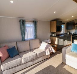 A living room with two sofas and a kitchen area with cabinets and appliances at Wansbeck View 2 in Ashington