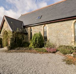Exterior of a stone building with stained glass windows and gravel driveway at The Chapel in Dol-y-Gaer near Pontsticill