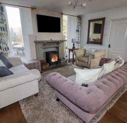 A living room with sofas a fireplace a wall-mounted TV and a wooden side table at The Chapel in Dol-y-Gaer near Pontsticill