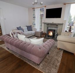 A living room with three sofas a fireplace and a wall-mounted television at The Chapel in Dol-y-Gaer near Pontsticill