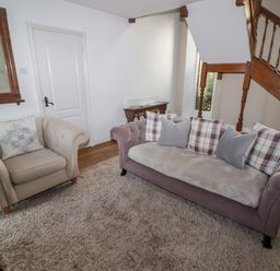 A sitting area with two sofas a large rug a mirror on the wall and wooden stairs at The Chapel in Dol-y-Gaer near Pontsticill