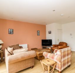 A living room with sofas a TV and wooden tables at The Lodge in Dol-y-Gaer near Pontsticill