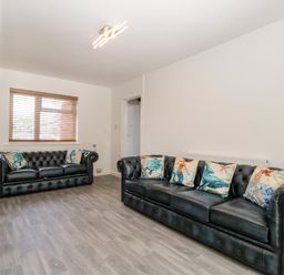 A living room with two black leather sofas and patterned cushions at Seacider in Burnham-On-Sea