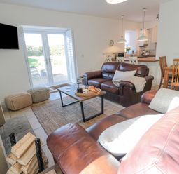 A living room with brown leather sofas coffee table and a dining table at Little Haven in Bamburgh