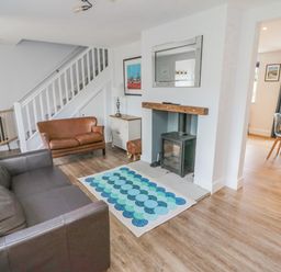 A living room with two sofas a wood burning stove and a rug at 3 St Cuthberts Garth in Bamburgh
