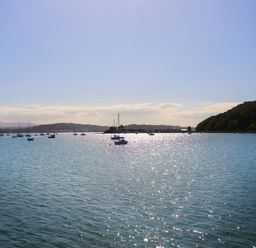 A body of water with boats and hills in the background at Bethania in Llangoed near Beaumaris