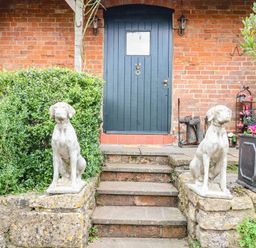 A front entrance with stone dog statues on either side of stairs leading to a dark wooden door at The Cheese Room in Stretton-On-Fosse