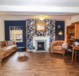 A sitting room with brown sofas a fireplace a wooden shelf and a small dining table at The Cheese Room in Stretton-On-Fosse