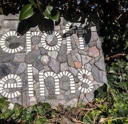 A mosaic stone sign with the words croft elms surrounded by green leaves and plants