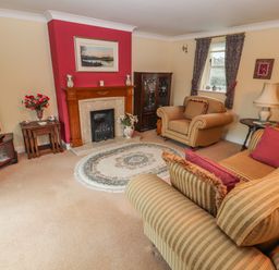 A living room with striped sofas a fireplace and a television at Bryn Offa cottage in Holywell