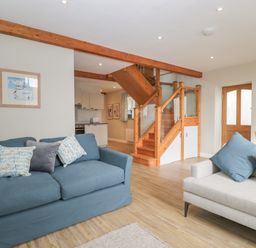 A living room with two sofas and wooden stairs leading to the upper floor at The Old Haberdashery in Swanage