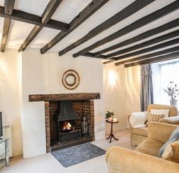 A living room with a fireplace armchairs a television and a window with curtains at Bwthyn Dwyfor in Beaumaris