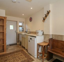 A kitchen with a sink, dishwasher, storage cabinet and a wooden bench at Buzzards Breg in Builth Wells