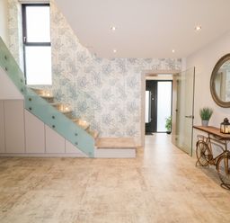 An entryway with stairs glass railing and a bicycle shaped table with a round mirror above at The Beachhouse in Meenlaragh near Gortahork County Donegal
