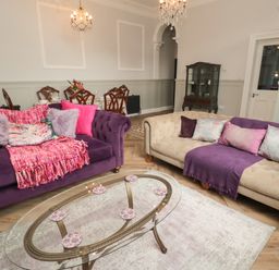 A living room with purple and beige sofas a glass coffee table and a dining table with chairs at The Vault House in Bellingham