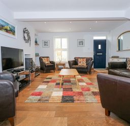 A living room with a television armchairs sofas a wooden coffee table and a colorful patchwork rug at Min Y Mor - Morfa Nefyn