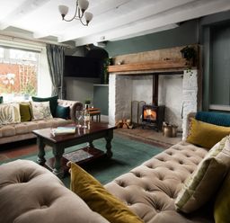 A living room with two sofas a wooden coffee table and a fireplace at Owl Cottage in Morpeth