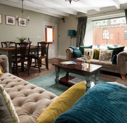 A living room with two sofas a coffee table dining table with chairs and a large window at Owl Cottage in Morpeth