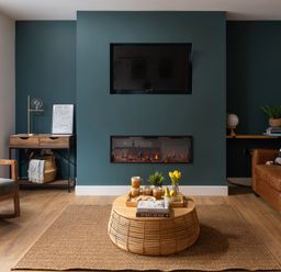 A living room with a mounted TV and electric fireplace a rocking chair and a brown leather sofa at Hebog in Beddgelert
