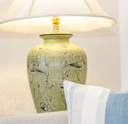 A table lamp with floral and bird design next to a striped cushion on a sofa at 3 St Davids Place in Llandudno
