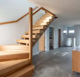 A hallway with wooden stairs glass railing and wooden sideboard with vase at The Old Coastguard Lookout in Port Isaac